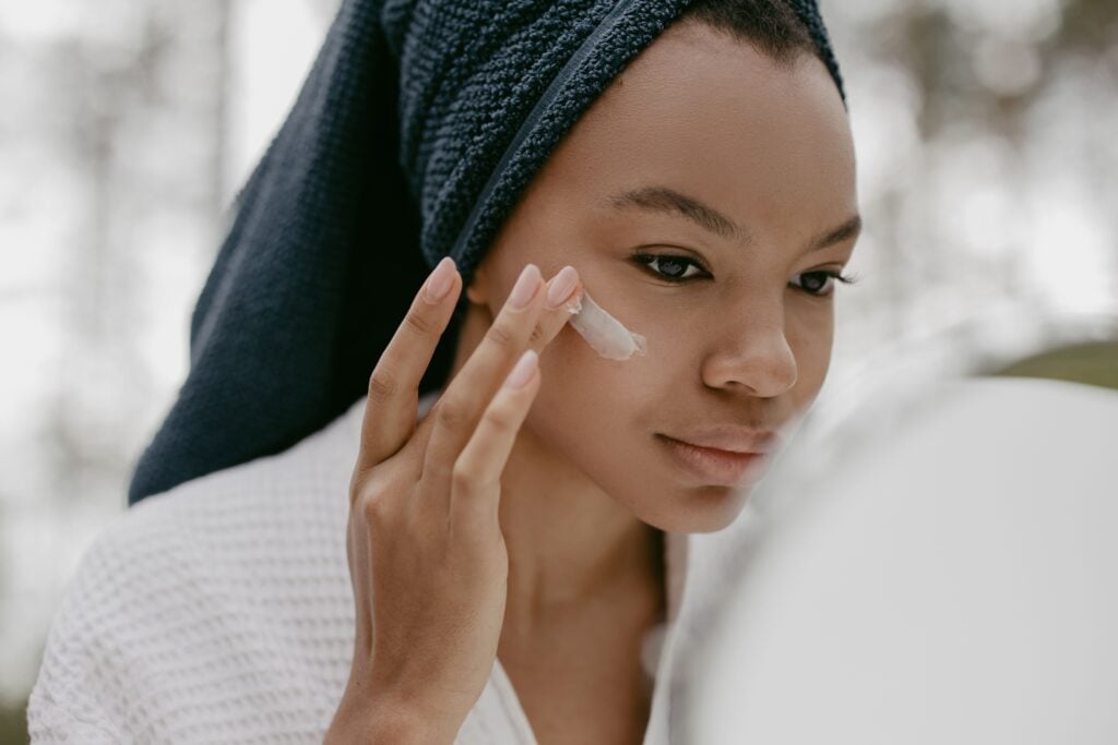 fall skin reset — woman applying moisturizer during seasonal skin transition